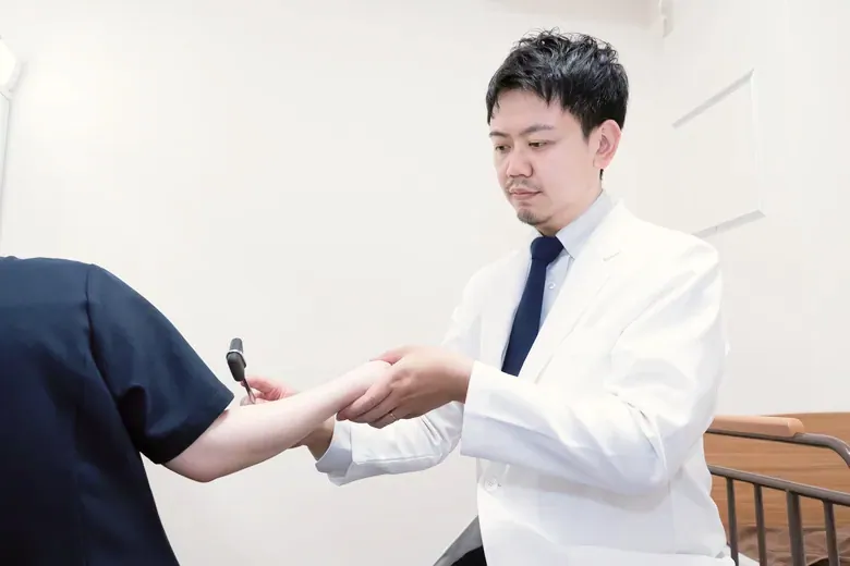 医師が患者の手の状態を確認している様子